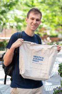 A man holds a bag with text reading "Health Is a Human Right"